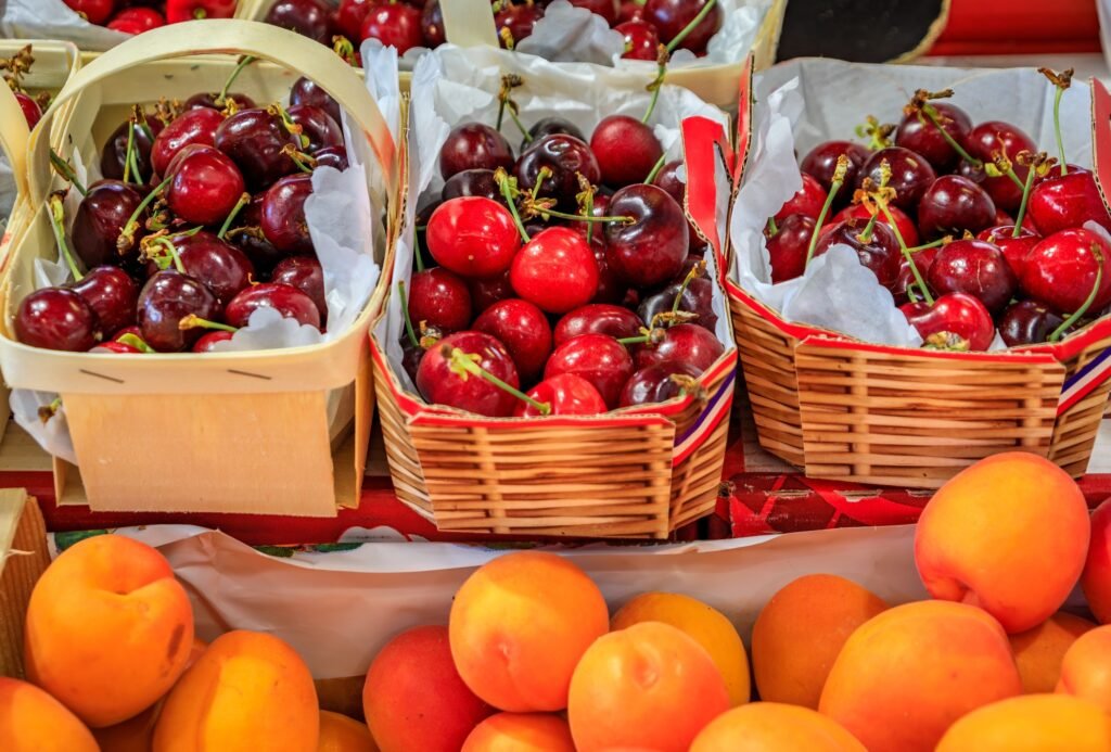 Fresh apricots and bright red cherries displayed at an open-air market stall in Provence