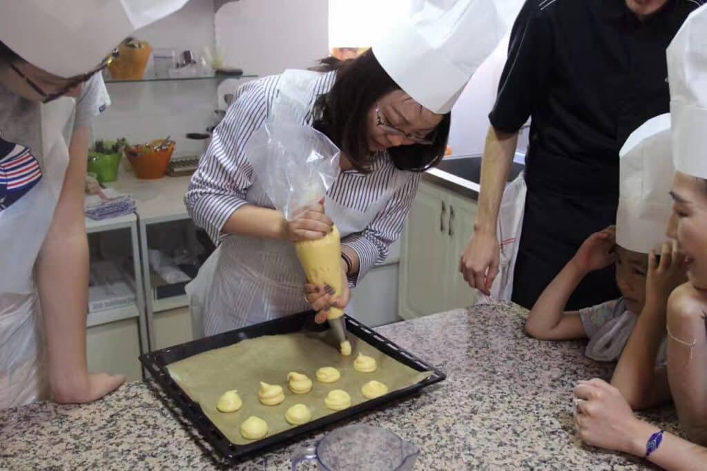 Hands-on French pastry workshop in Provence with participant piping choux pastry